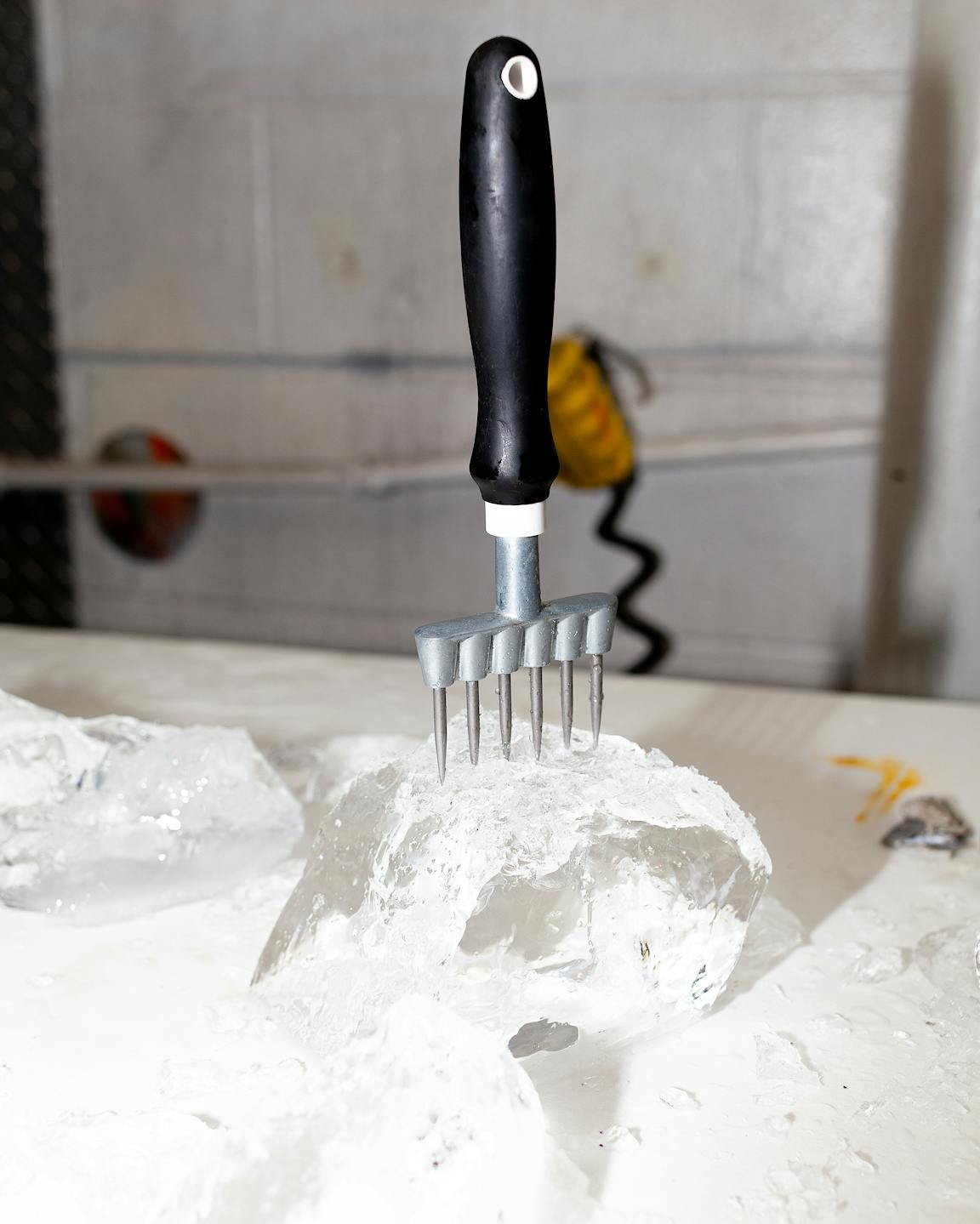 A pronged hand tool protrudes from a chunk of ice.